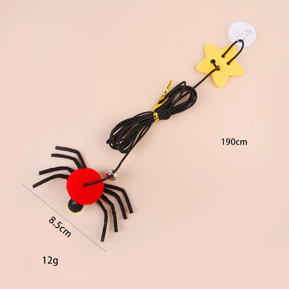 Red door hanging cat toy with elastic rope, feather, bell, and spider attachment on a white door.