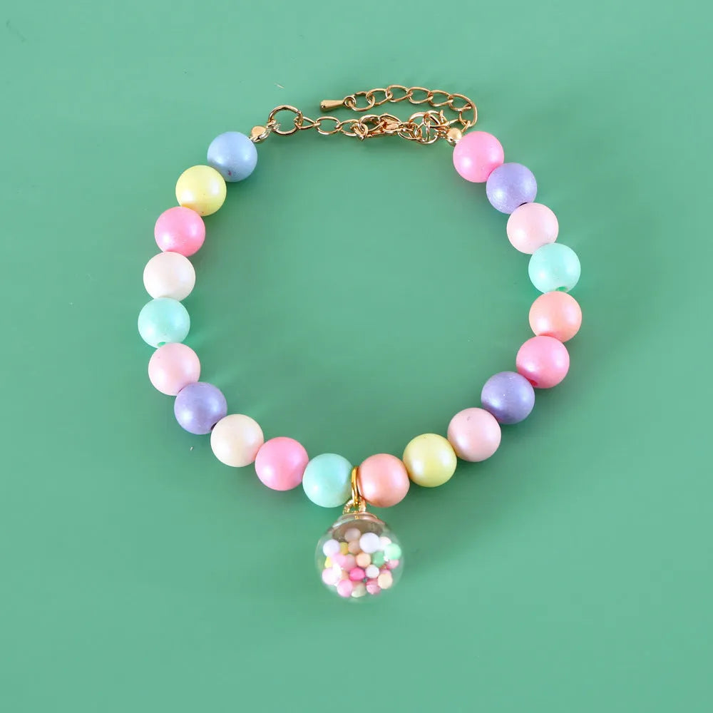 Macaron-coloured resin pet collar and bracelet set for birthday photoshoots on a neutral background.