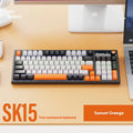 SK15 wired mechanical keyboard with volume knob in sunset orange colour beside laptop