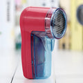 Blue portable electric lint remover for clothing, showing compact size next to a sweater.