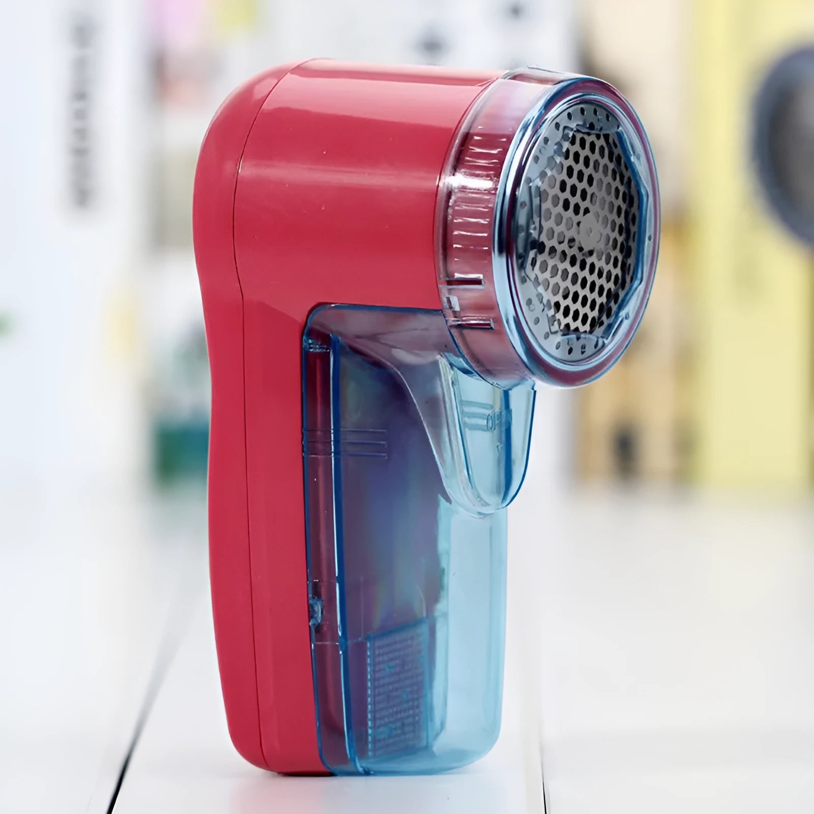 Blue portable electric lint remover for clothing, showing compact size next to a sweater.