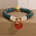 Blue water jade bead bracelet with red agate peace buckle closure and rhinestone details
