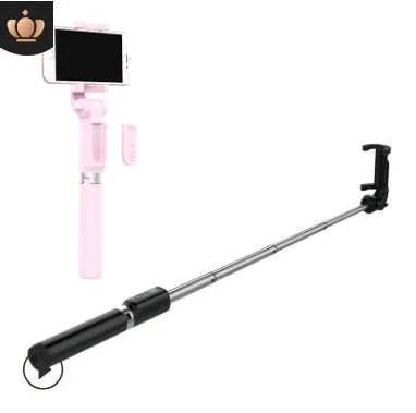 Black Bluetooth selfie stick with extended tripod legs and remote control next to a mobile phone.