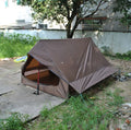 Brown or white A-line cabin tent pitched with trekking poles, showing spacious interior and waterproof fabric construction