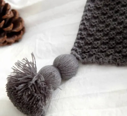 Acrylic knitted blanket with fringed edges in a neutral colour on a sofa.
