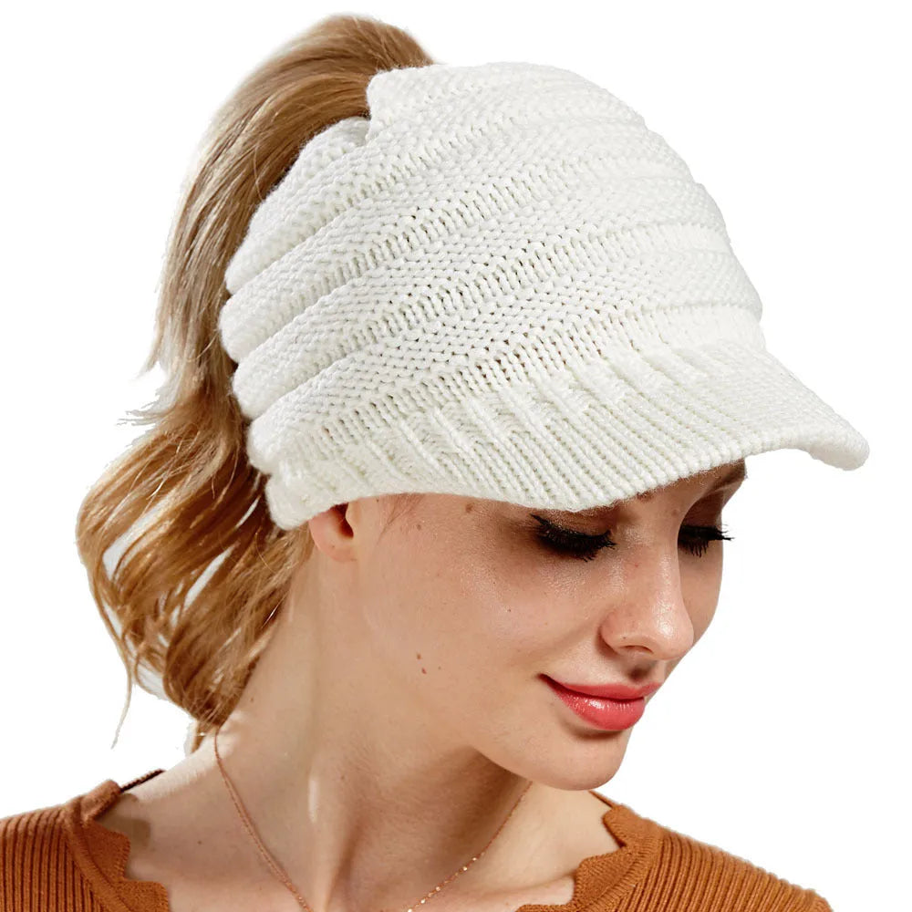 Woman wearing a soft knitted beanie with a ponytail pulled through the hole at the back.