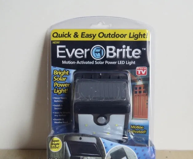 Set of four white solar-powered LED security lights with motion sensors mounted on an outdoor wall.