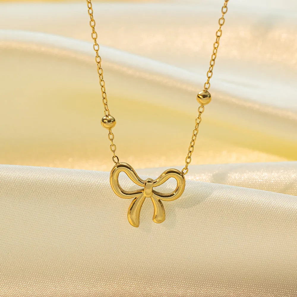 Gold electroplated titanium steel women's necklace with bow pendant and adjustable cross chain
