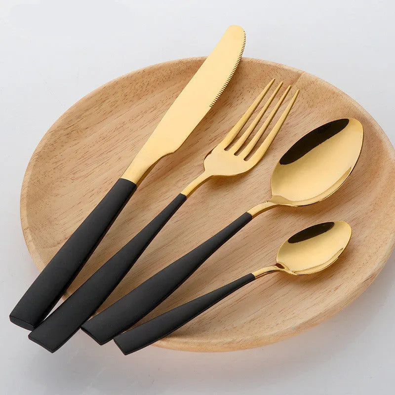 Four-piece stainless steel cutlery set with mirror-polished black finish laid out on a surface