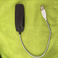 Black flexible gooseneck USB LED lamp with clip, illuminating a book.