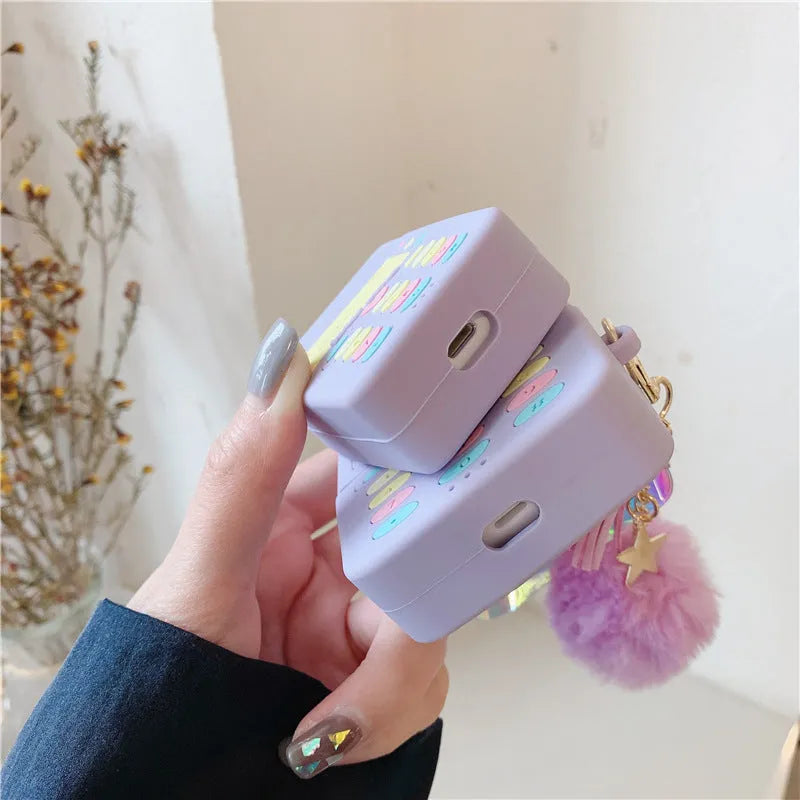 Purple silicone clamshell case for Apple AirPods with a white fur ball pendant attached.