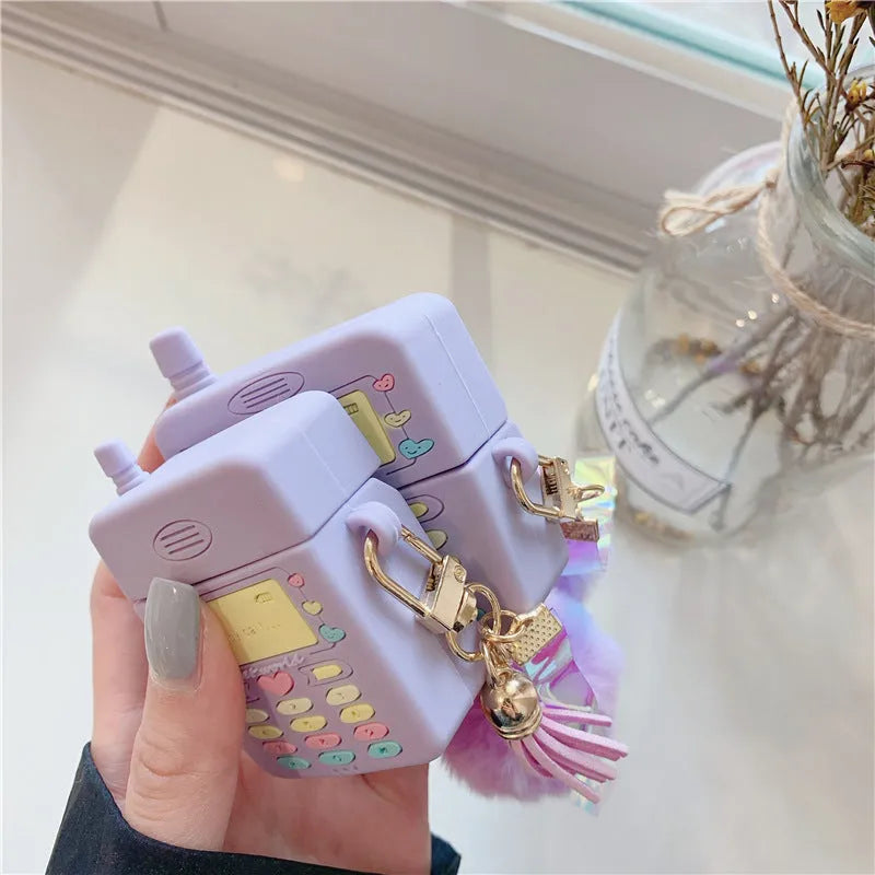 Purple silicone clamshell case for Apple AirPods with a white fur ball pendant attached.