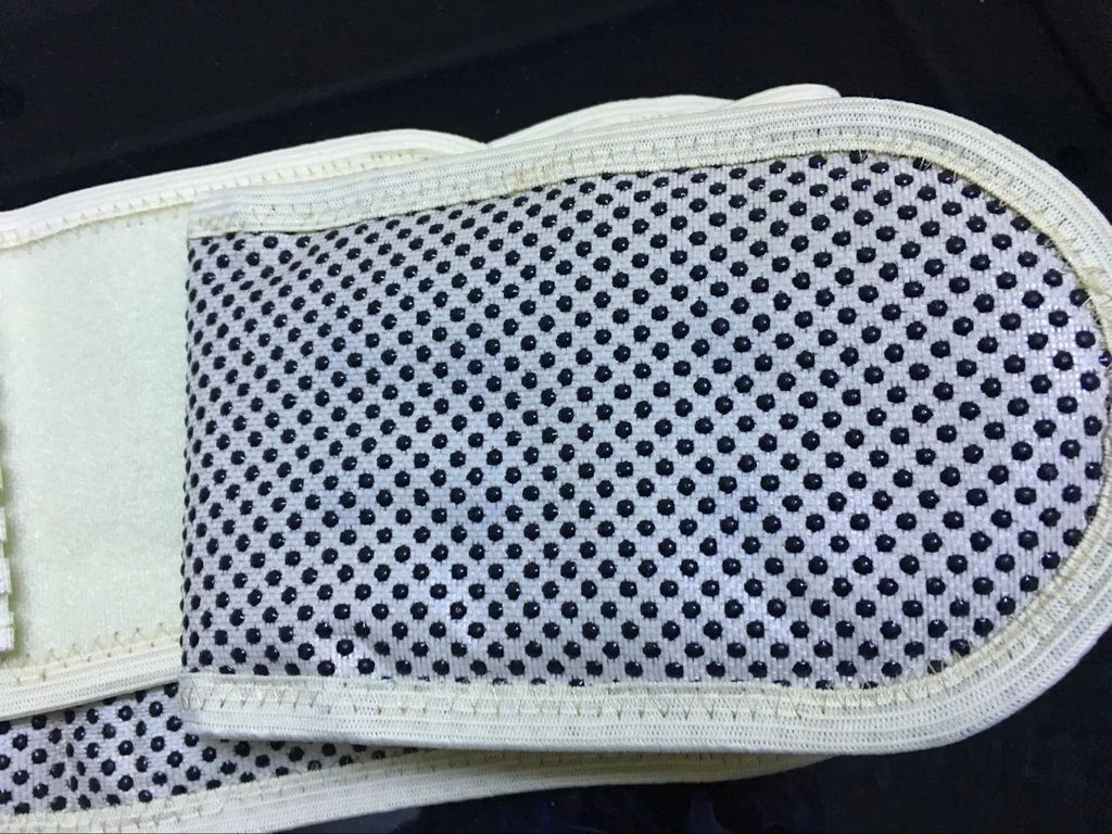 Black self-heating waist protection fixed belt with magnetic therapy for lumbar support on a beige background.