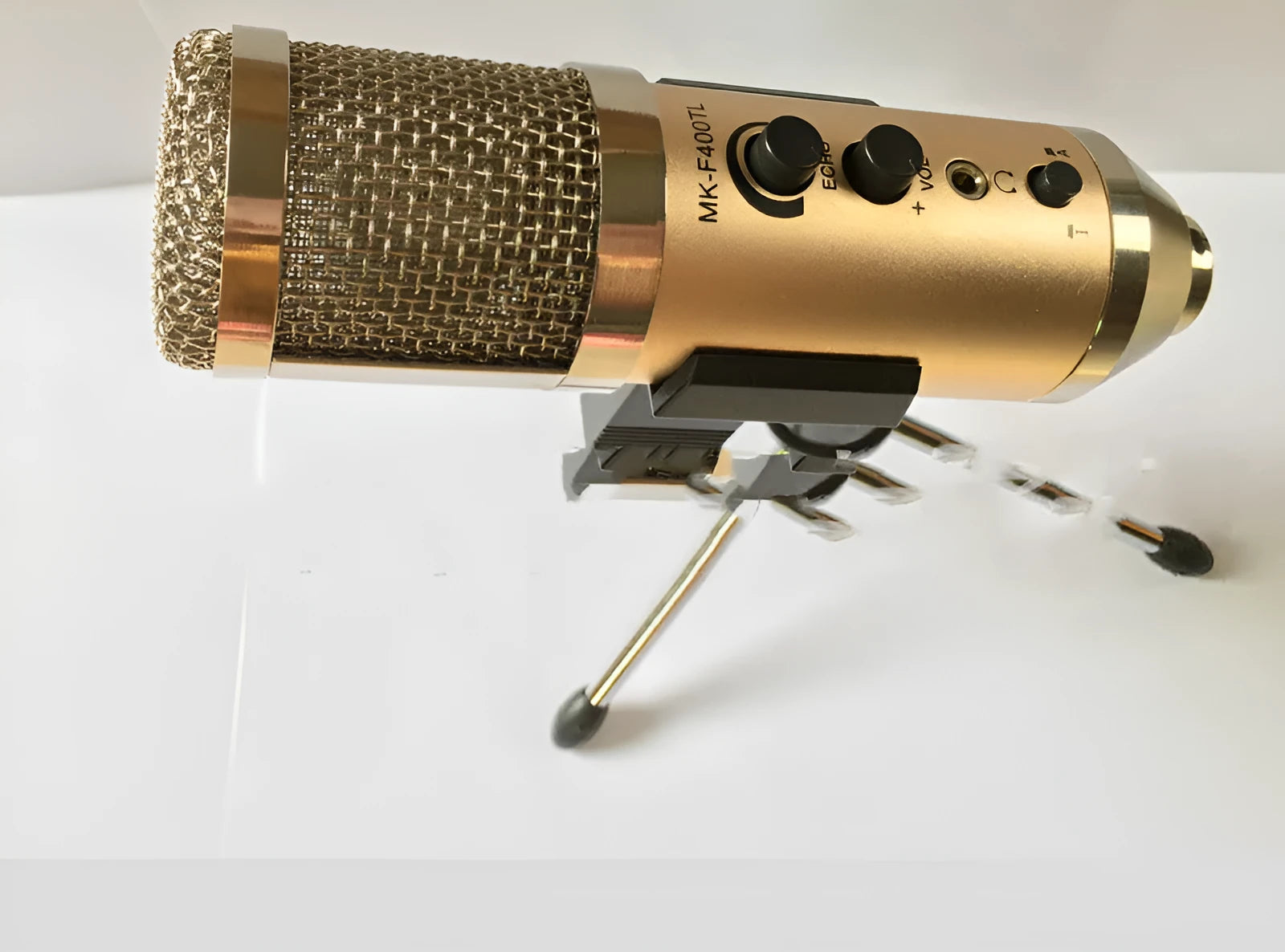 Gold coloured USB condenser microphone with bracket on a desk.
