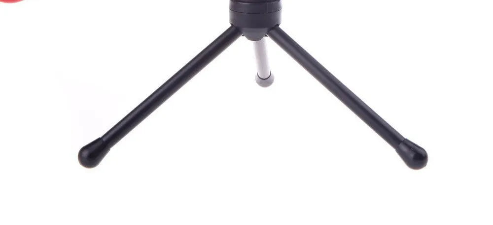 Black wired computer microphone with mounting bracket on desk next to laptop