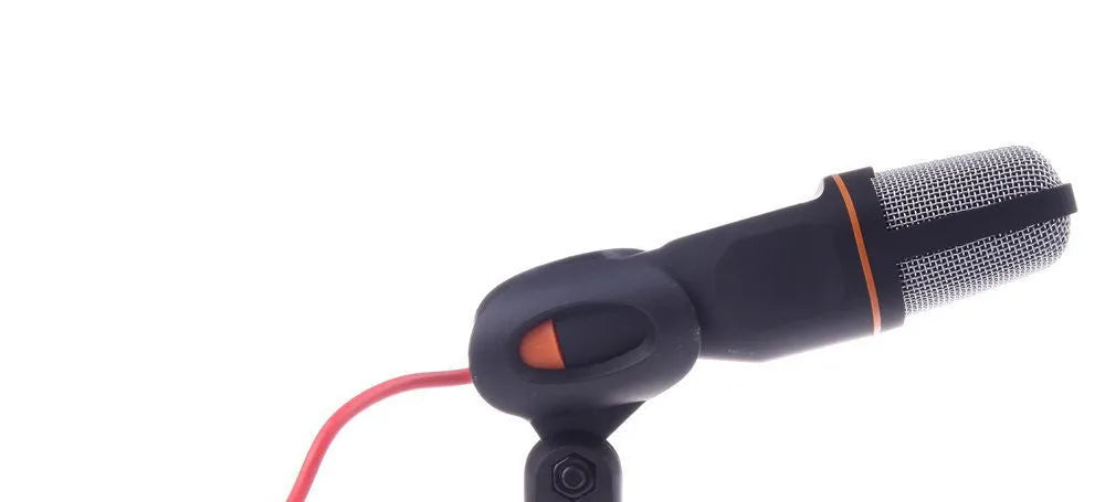 Black wired computer microphone with mounting bracket on desk next to laptop