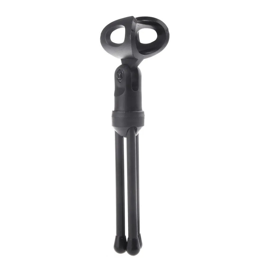 Black wired computer microphone with mounting bracket on desk next to laptop