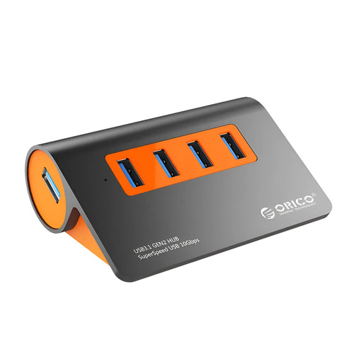 Dark grey aluminium USB hub with orange accents showing four USB 3.1 ports and separate power supply