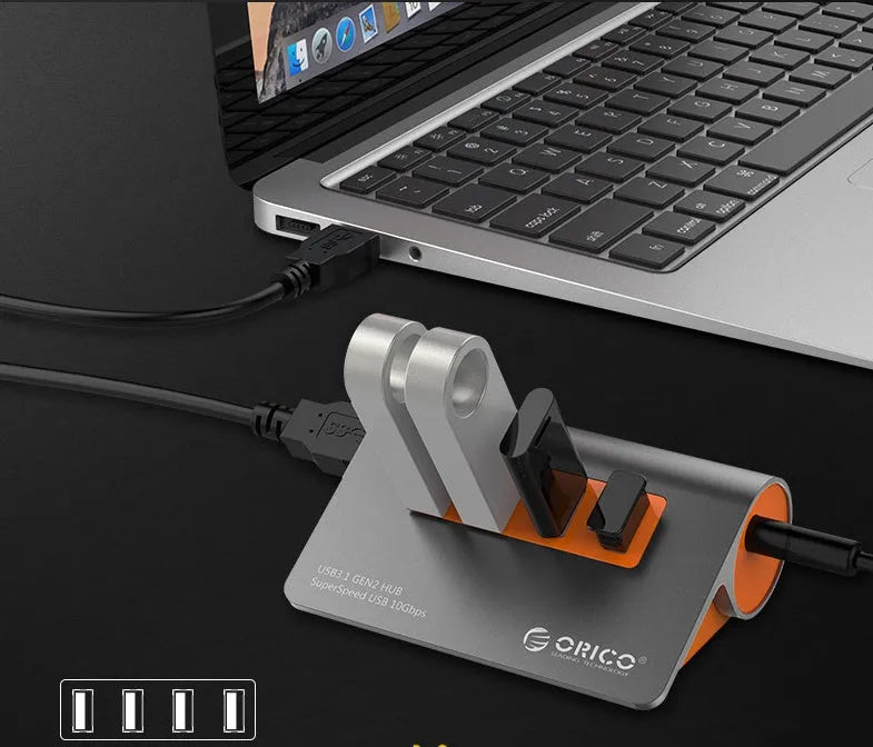 Dark grey aluminium USB hub with orange accents showing four USB 3.1 ports and separate power supply