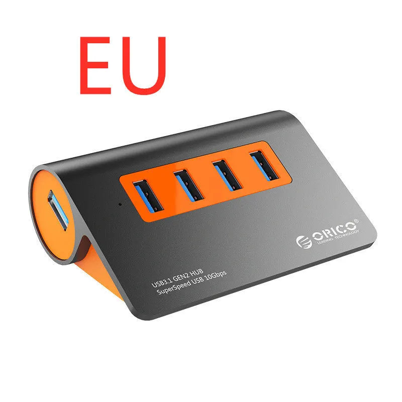 Dark grey aluminium USB hub with orange accents showing four USB 3.1 ports and separate power supply