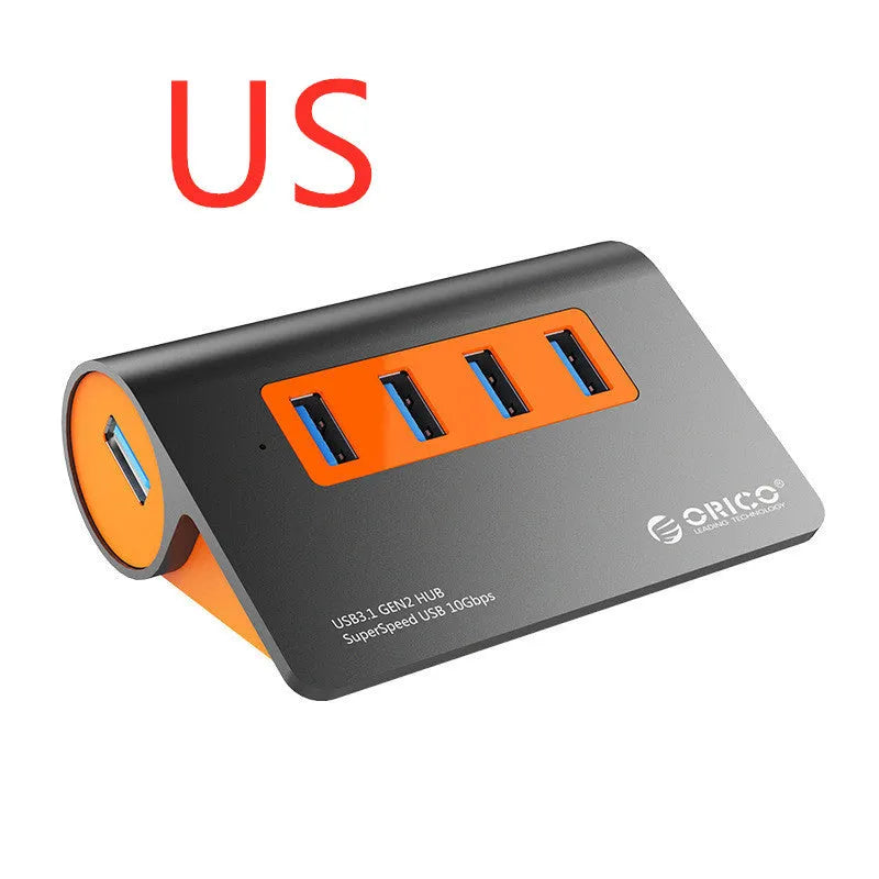 Dark grey aluminium USB hub with orange accents showing four USB 3.1 ports and separate power supply