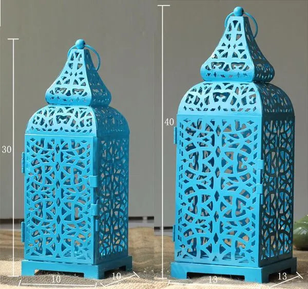Blue geometric iron Moroccan tea light lantern candelabra with hanging ornaments on a table.