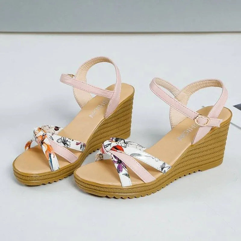 Women's pink wedge sandals with a thick platform heel and buckle strap.