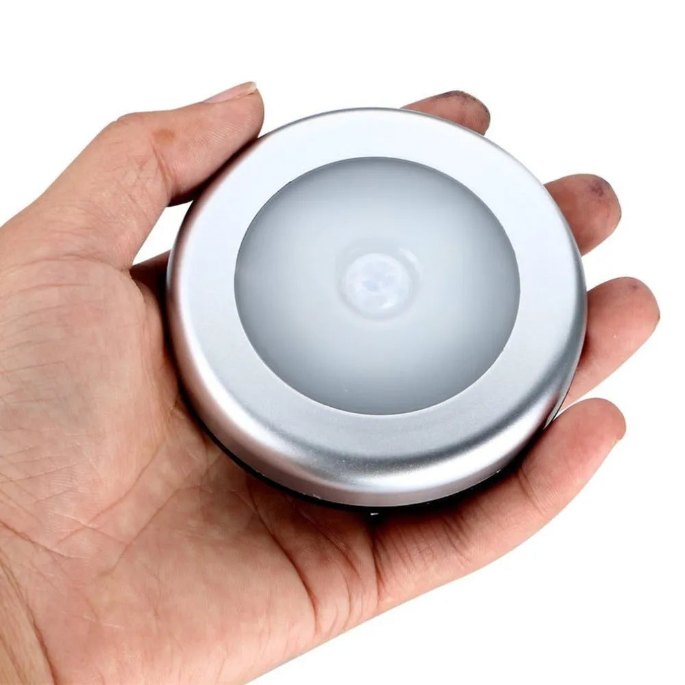 Silver square battery-operated motion sensor night light for automatic illumination.