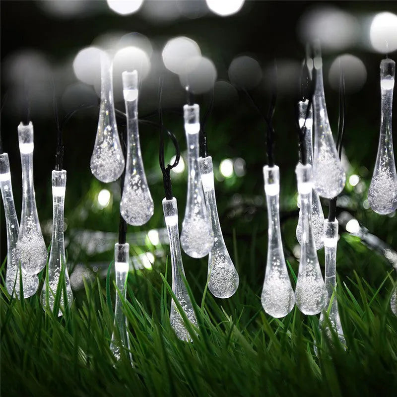 Solar-powered water drop LED string lights in garden with ground spike and bubble pendant design