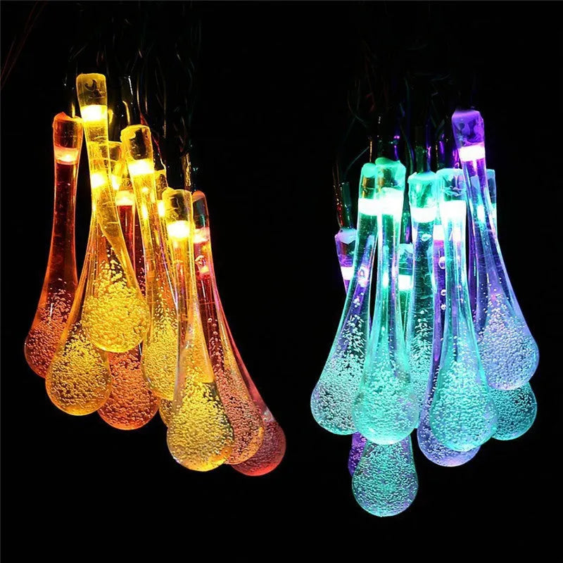 Solar-powered water drop LED string lights in garden with ground spike and bubble pendant design