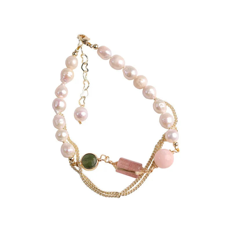 Close-up of a women's pink freshwater pearl bracelet with a geometric strawberry crystal charm on a silver chain.