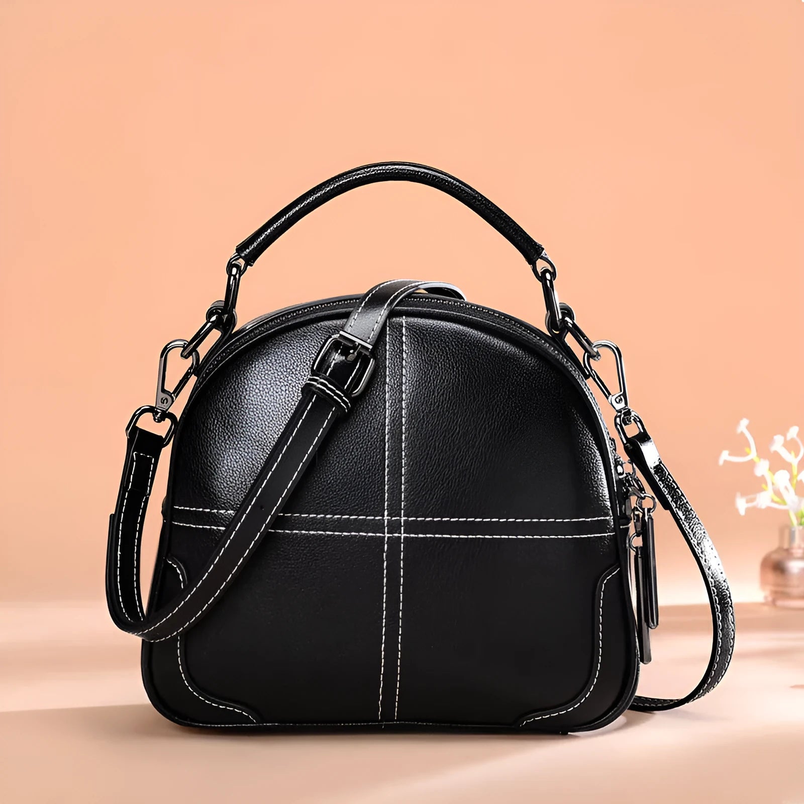 Round leather handbag with zip closure and soft double handles in wine red colour