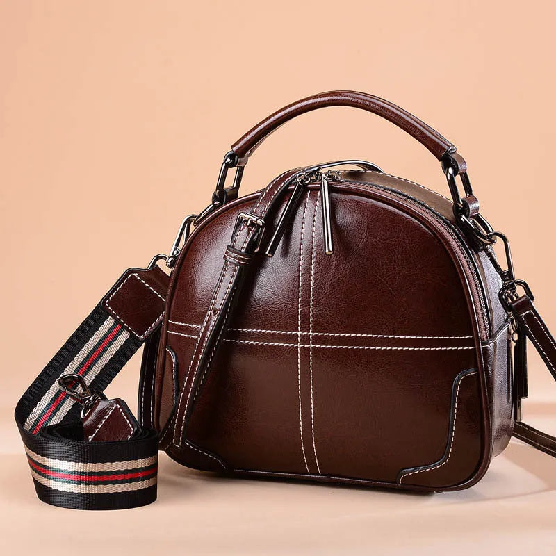 Round leather handbag with zip closure and soft double handles in wine red colour