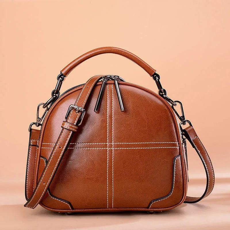 Round leather handbag with zip closure and soft double handles in wine red colour