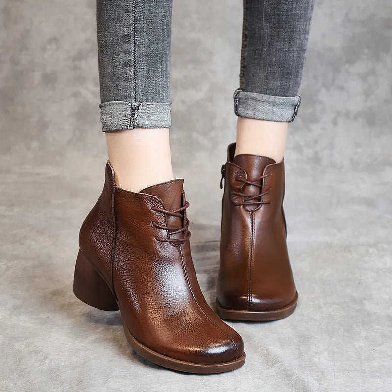 Women's brown leather Martin boots with a thick block heel and round toe on a wooden floor.