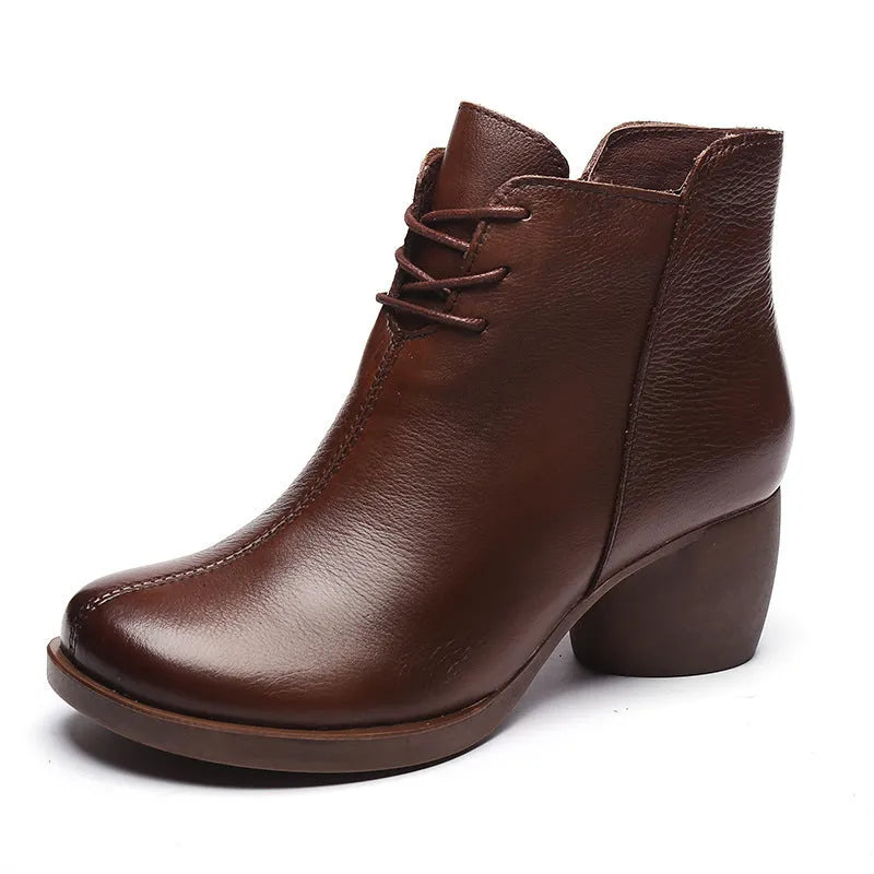 Women's brown leather Martin boots with a thick block heel and round toe on a wooden floor.