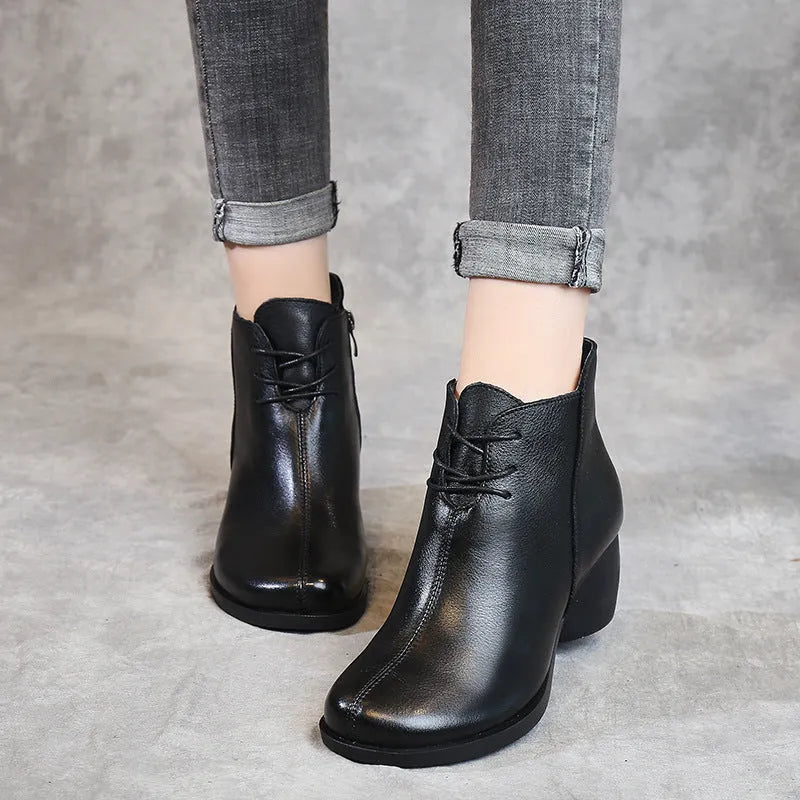 Women's brown leather Martin boots with a thick block heel and round toe on a wooden floor.