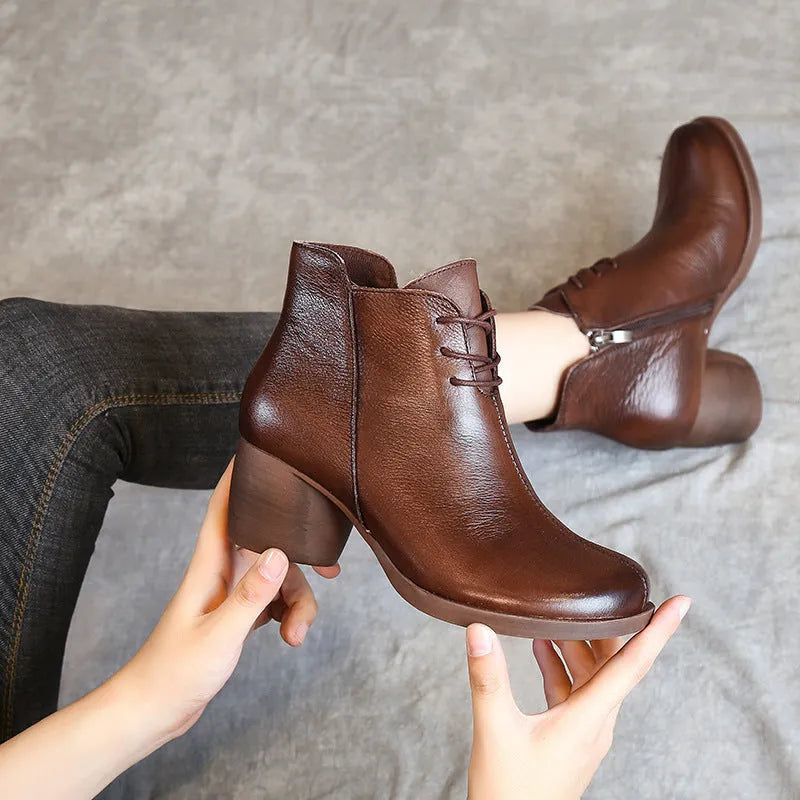 Women's brown leather Martin boots with a thick block heel and round toe on a wooden floor.