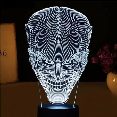 3D LED table lamp showing seven colour options with remote control and USB cable on wooden surface