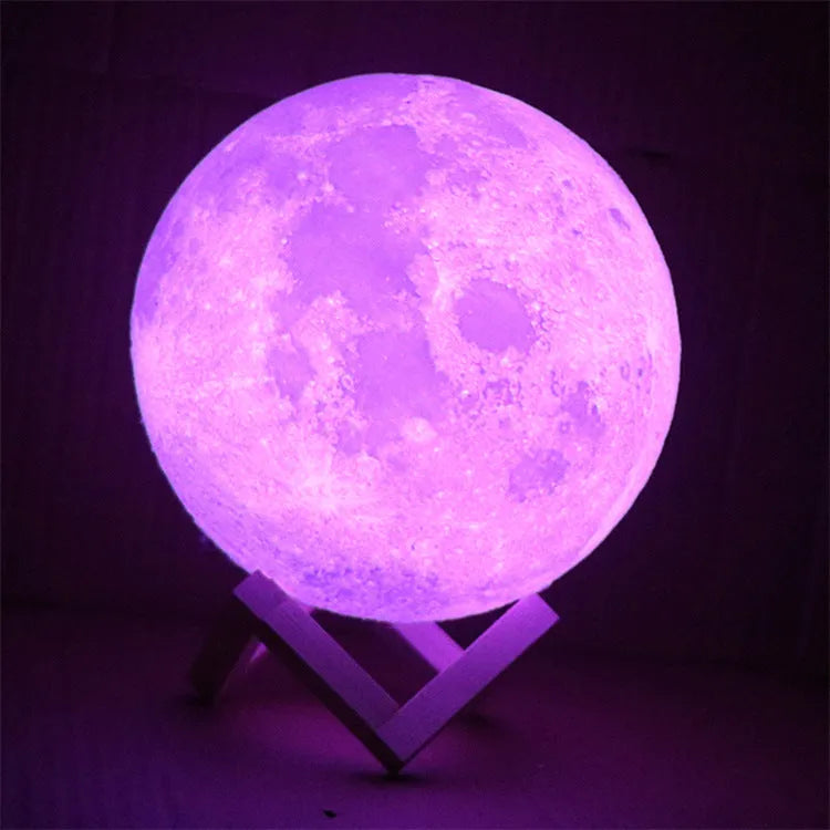 3D printed moon lamp glowing on a wood stand, showing detailed crater texture.