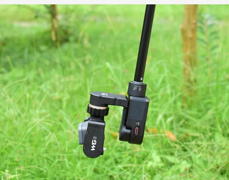 Black aluminium retractable selfie stick extended to full length with phone attached, showing included tripod stand and wireless remote.