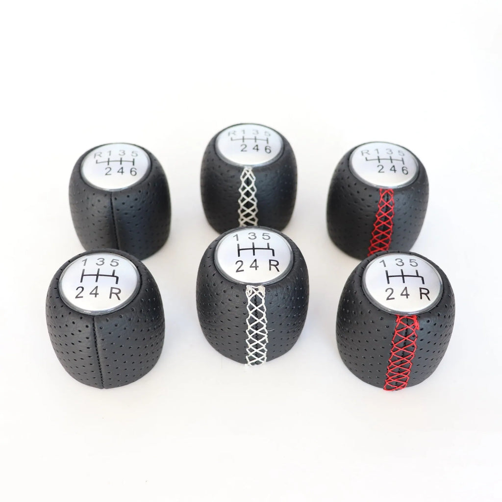 Sewn wrapped black perforated leather gear shift handball for Alpha vehicles on a silver cover.