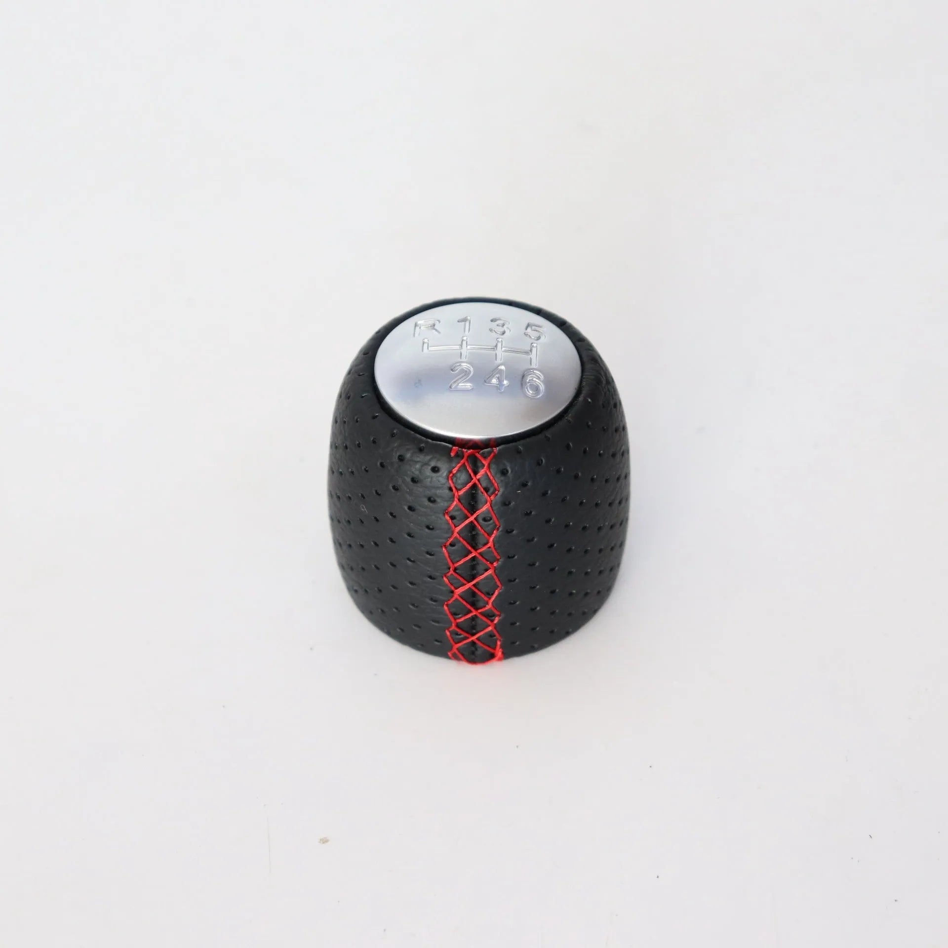 Sewn wrapped black perforated leather gear shift handball for Alpha vehicles on a silver cover.