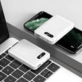 White or black large capacity portable power bank with multiple USB ports, shown next to a smartphone.