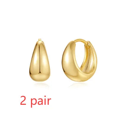 A pair of simple geometric brass earclip earrings with a round element and electroplated golden finish.
