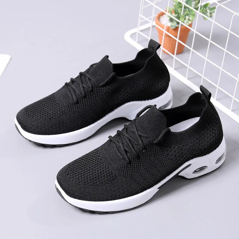 Women's black mesh casual sneakers with round toe and white lace-up front on a grey PVC sole.