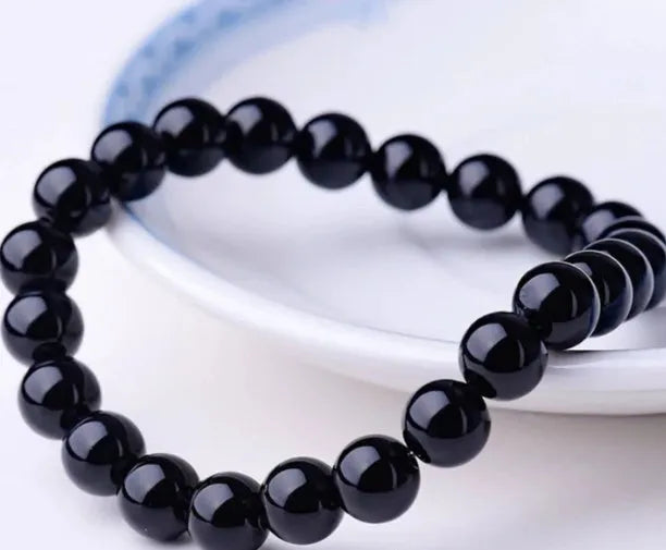 Women's geometric black agate bracelet with 8mm beads on a black elastic cord.