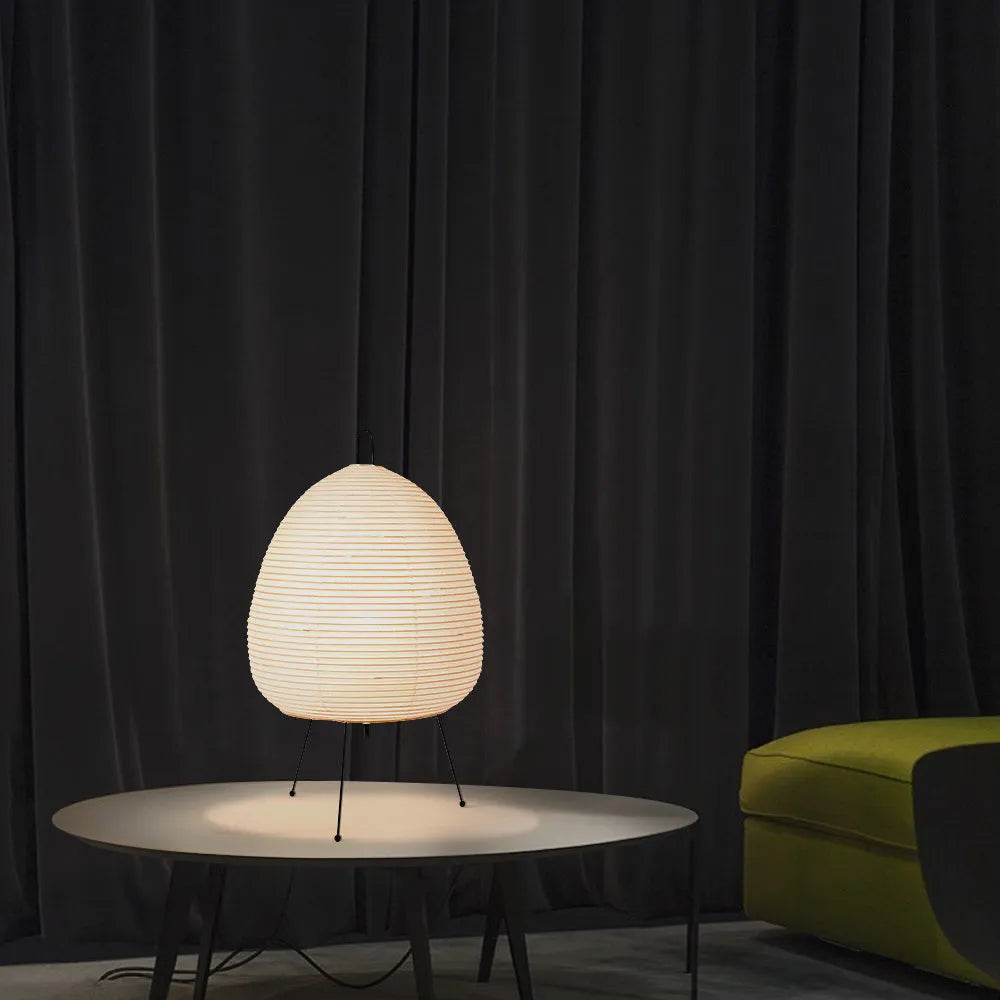 Japanese style handmade rice paper lantern table lamp with aluminium base on a wooden table.