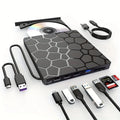 Black external USB CD/DVD writer and reader drive on a desk next to a laptop.