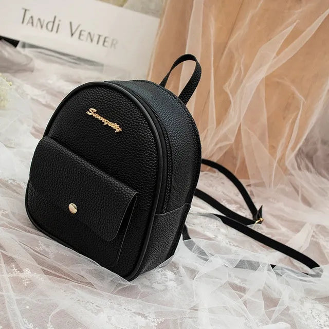 Small black PU shoulder backpack for women with zipper, shown next to a mobile phone for scale.